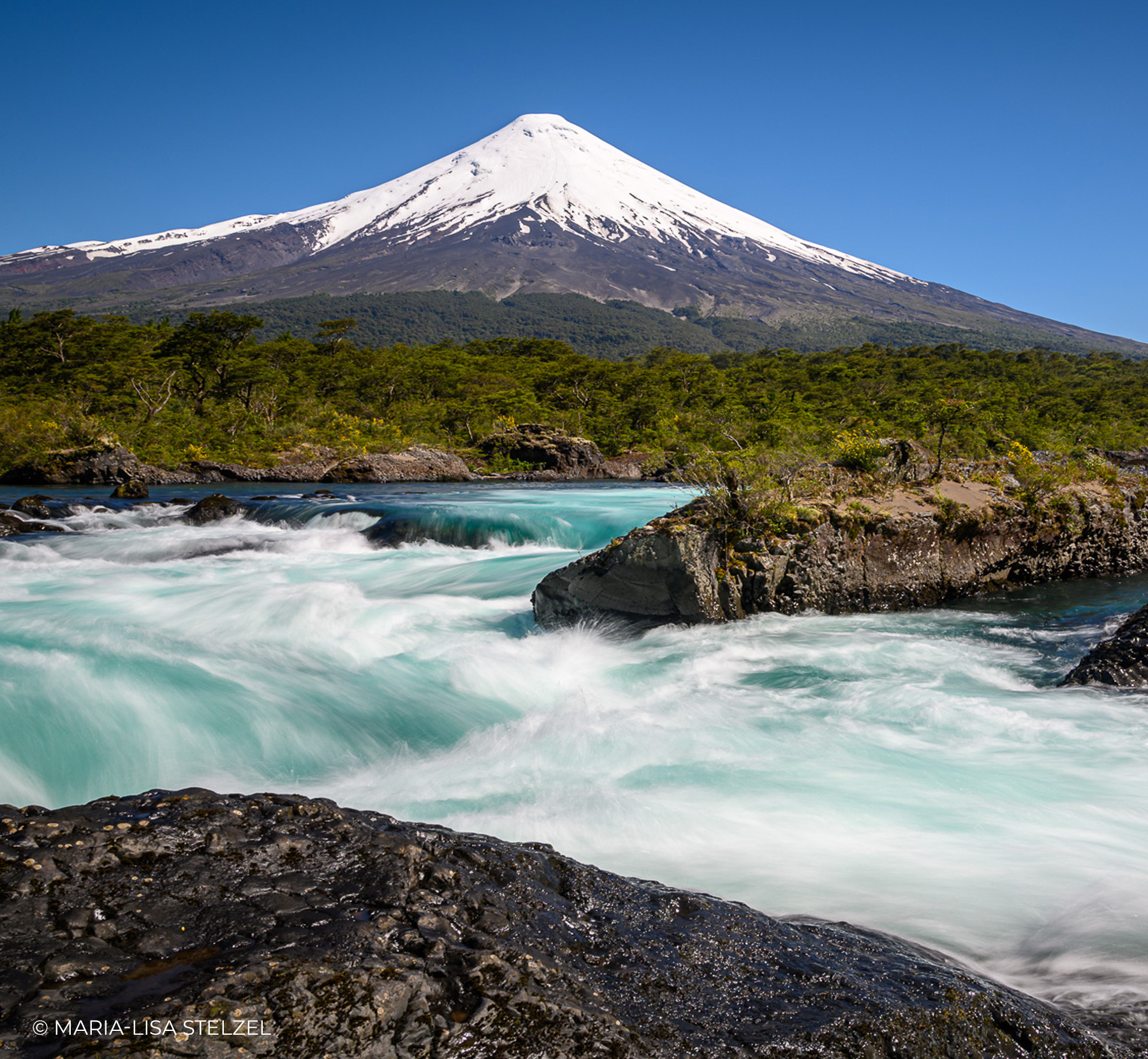 Schneebedeckter Vulkan Osorno über den türkisen Wasserfällen von Petrohué in Chile, Langzeitbelichtung von Maria-Lisa Stelzel
